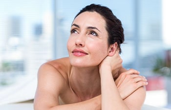 Smiling brunette relaxing on massage table in a healthy spa
