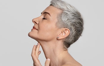 Profile of beautiful middle-aged woman touching soft skin on her neck