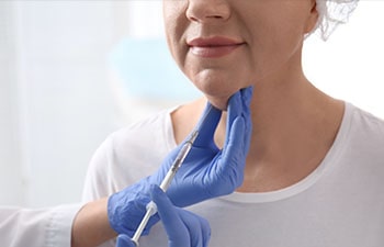 Mature woman with double chin receiving injection in clinic