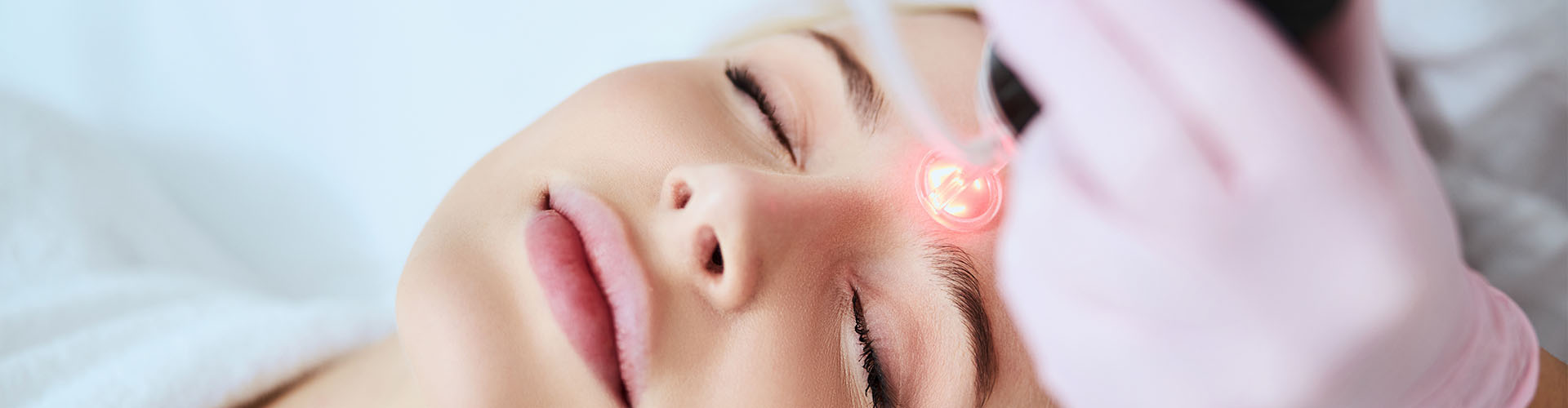 Tranquil female patient lying with closed eyes during the laser treatment in a beauty clinic