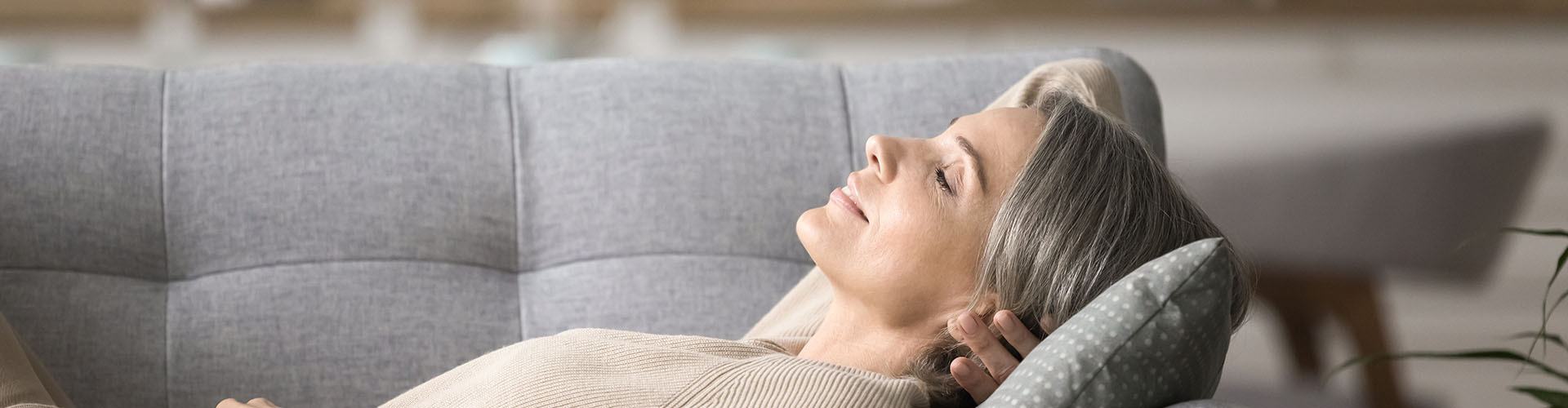 Calm serene early senior age lady take break to relax at day time lying on back on comfortable couch
