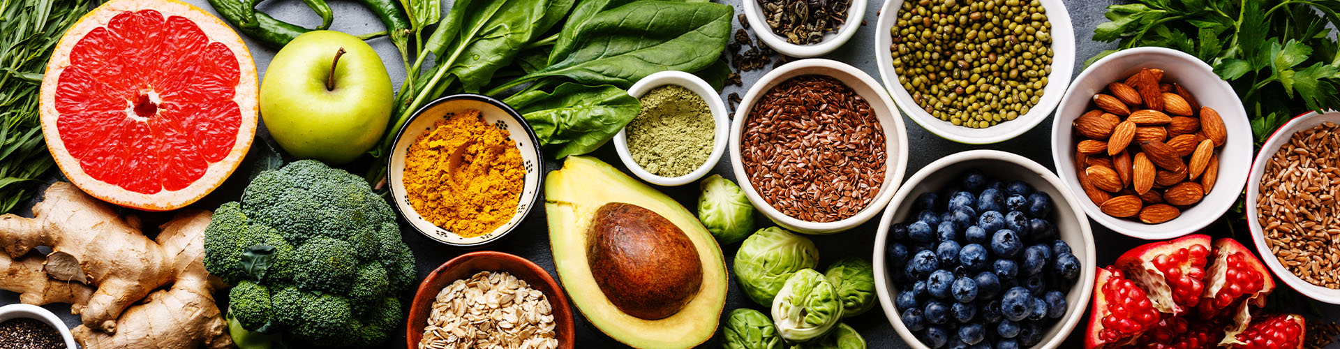 Healthy food clean eating selection: fruit, vegetable, seeds, superfood, cereal, leaf vegetable on gray concrete background