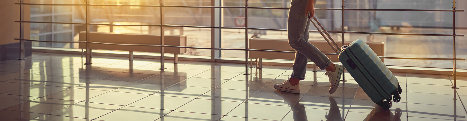 young woman goes at airport at window with a suitcase waiting for plane